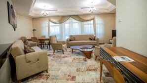Ein Wohnzimmer mit einer Couch, Sesseln, einem Couchtisch und einem Fernseher.