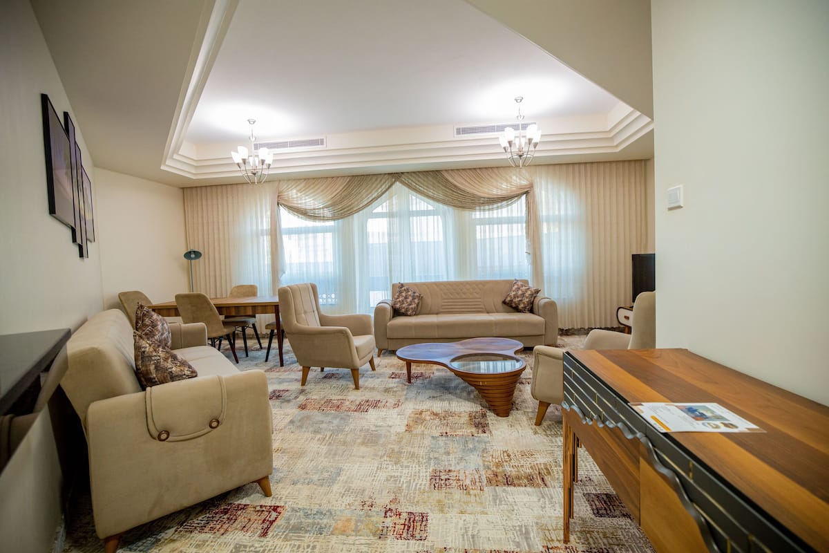 A living room with a sofa, armchairs, a coffee table, and a TV.