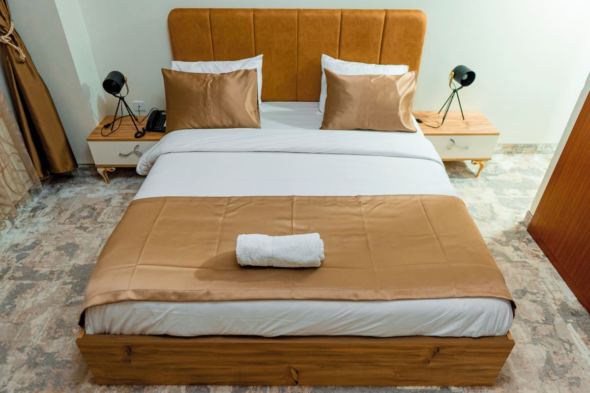 A bed with a wooden headboard, two bedside tables, and a white blanket.