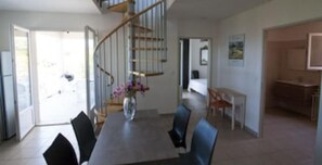 Stylish dining area with a staircase leading to an upper level, featuring a kitchen area and modern design.