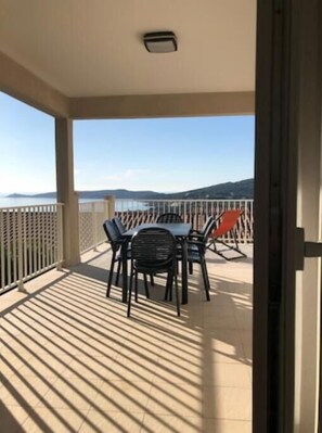 Enjoy the ocean view from this balcony with a table and chairs.