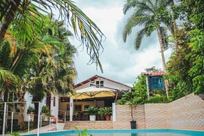 A pool area with a building, palm trees, and a sign.