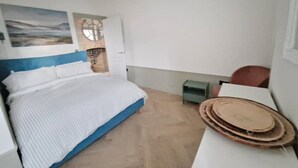 Une chambre à coucher comprenant un lit, une petite table, une chaise, une horloge murale et un élément décoratif mural.