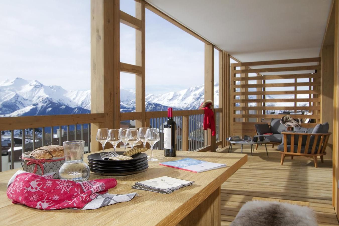 Terraza de madera con una mesa lista para comer, con vistas a un paisaje montañoso.