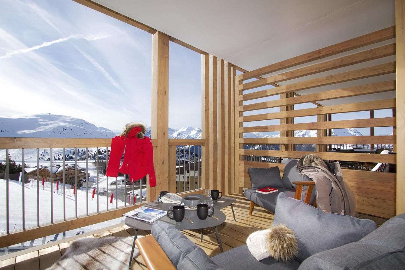 A cozy room with a wooden slatted wall, a sofa, and a table with a book and a mug.