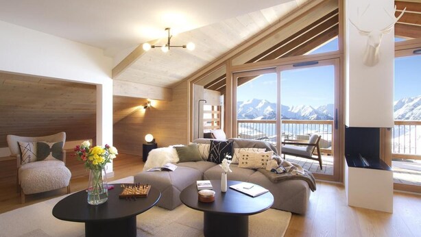 Un vaste espace de vie avec une grande fenêtre donnant sur un paysage montagneux enneigé. On y trouve un coin salon confortable avec un canapé et une table basse, ainsi qu'une cheminée décorée d'une tête de cerf.
