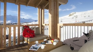 Une terrasse en bois offrant une vue sur une montagne enneigée et une piste de ski.