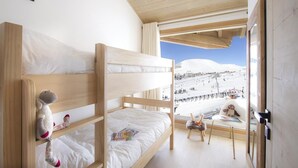 Une chambre avec des lits superposés et vue sur les pistes de ski.