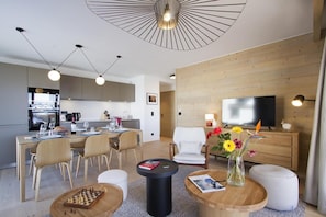 Uma sala de estar moderna com área de jantar, televisão e parede de madeira.