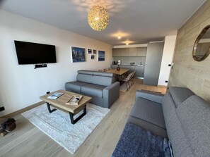 A modern living room with grey sofas, a wooden coffee table, and a flat-screen TV mounted on the wall. - Ground floor, fitness, swimming pool, sauna, hammam, terrace, tv, ski locker, 55m², Alpe d'Huez (Huez)