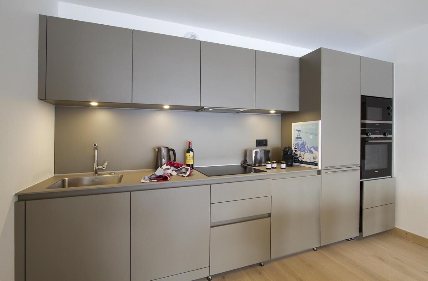 A modern kitchen with a built-in oven, a sink, and a coffee maker.
