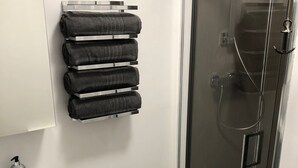 Une salle de bain avec une douche à parois de verre, un lavabo blanc et un porte-serviettes avec des serviettes pliées.