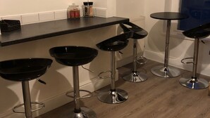 Une cuisine avec un plan de travail noir, quatre tabourets de bar et deux panneaux décoratifs encadrés accrochés au mur.