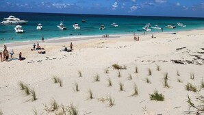 Une plage où plusieurs bateaux sont amarrés dans l’eau et où des personnes se trouvent sur le sable.