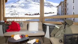 Un espace extérieur accueillant, aménagé avec des sièges confortables, offrant une vue sur des montagnes enneigées.