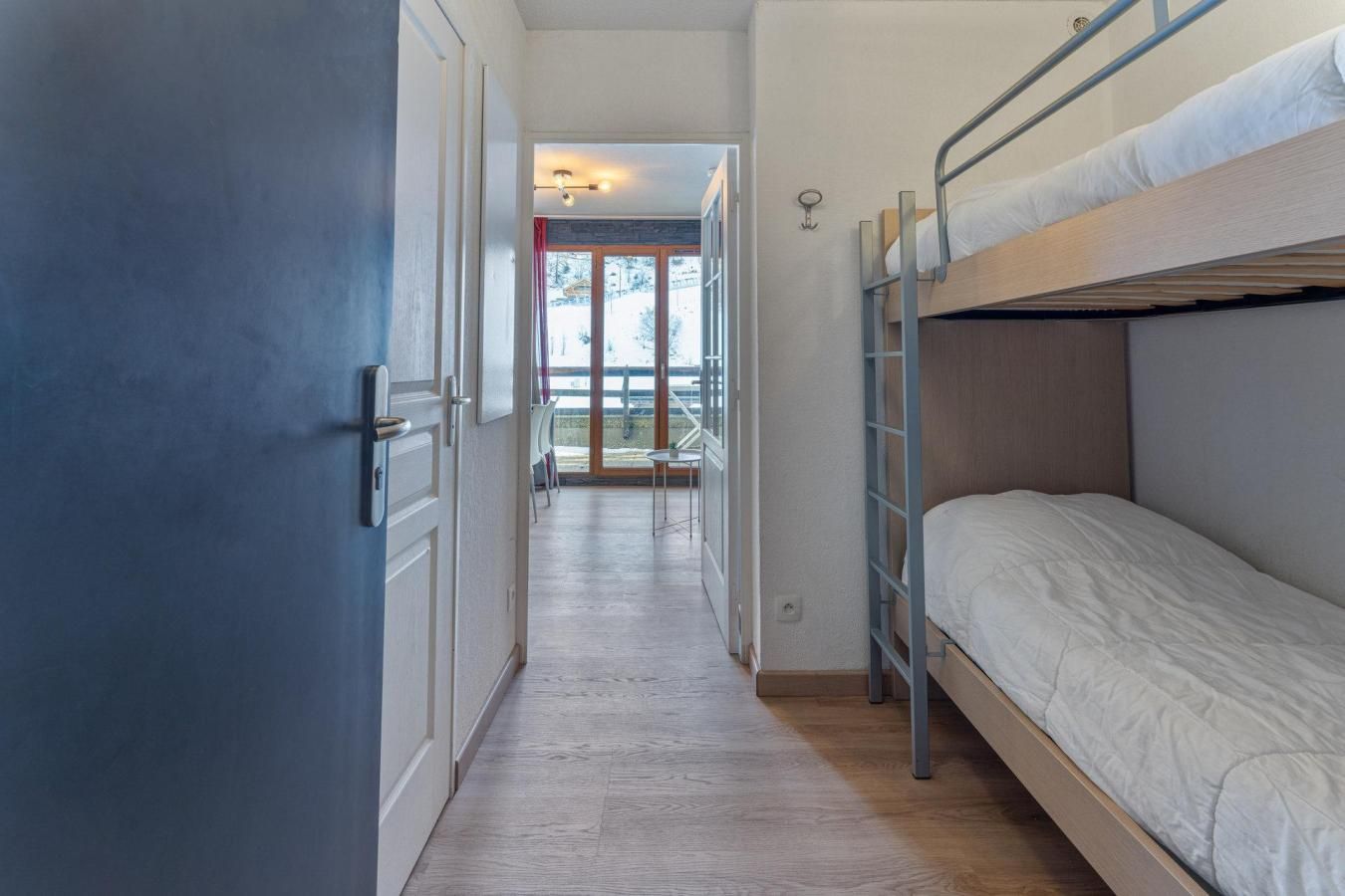 En smal hall som leder ut till en balkong, och till höger finns en våningssäng.