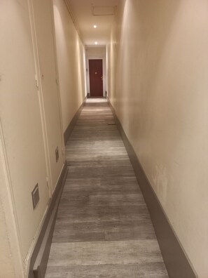 A long, narrow hallway with a wooden floor and beige walls. - Appartement au Coeur de Bayeux (Bayeux)