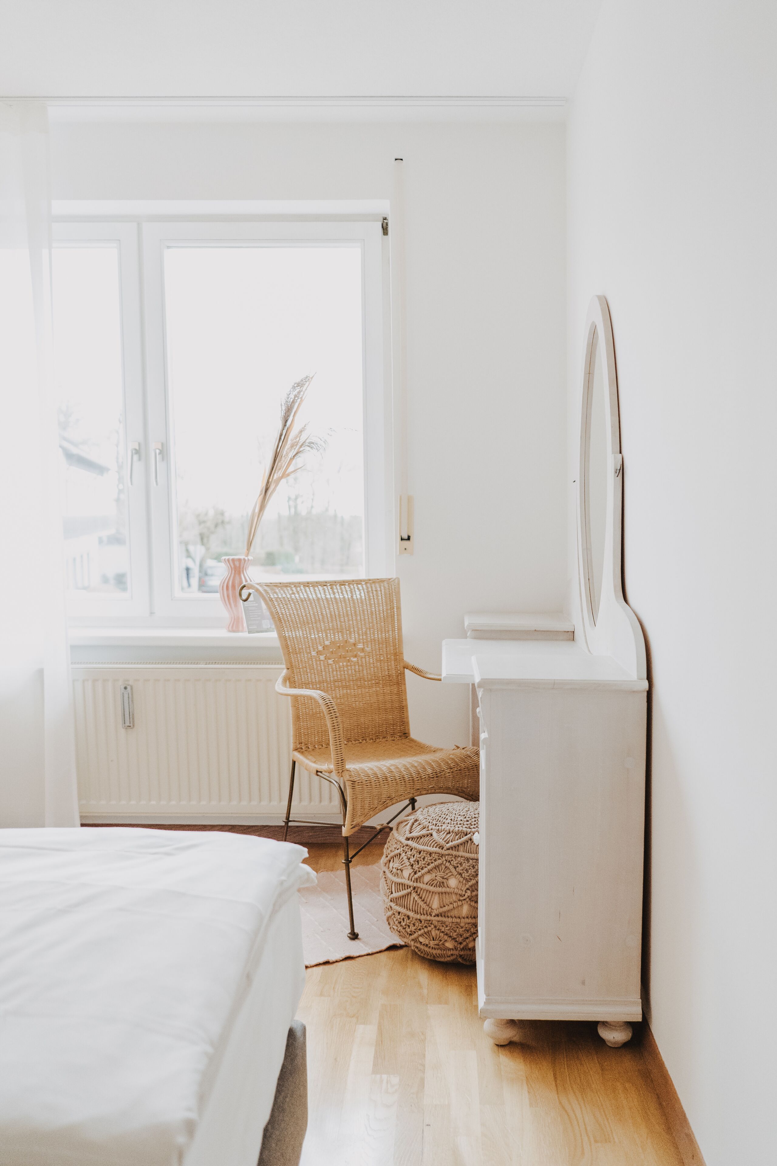 A bedroom with a bed, a chair, a dresser, and a window with a view of the outside.