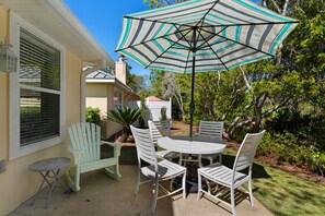 Een terras met een ronde tafel, vier stoelen, een parasol en een bijzettafeltje.