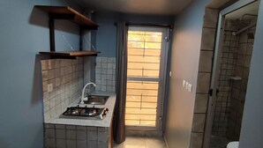 Una cocina estrecha con estufa a gas, un lavamanos y una ventana que da al exterior.