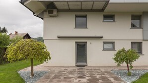 A two-story building with a flat roof, a central entrance door, and small windows on each floor. - BLED - Flamingo apartment (Bled)