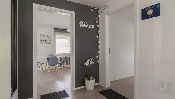 A modern interior with a 'Welcome' sign, a potted orchid, and a dining area with chairs and a table. - BLED - Flamingo apartment (Bled)