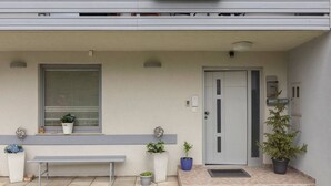 A modern building entrance with a bench, potted plants, and a door. - BLED - Flamingo apartment (Bled)