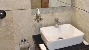 Une salle de bain avec un lavabo blanc, un miroir et un porte-serviettes.