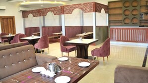 Un restaurant avec des banquettes et des tables, certaines étant équipées d’assiettes et de couverts.