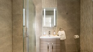 Un bagno moderno con box doccia in vetro, un mobile bagno in legno con specchio e il water.