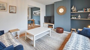 Ein modernes Wohnzimmer mit einem weißen Couchtisch, blauen Sofas, einem Fernseher und einem Bücherregal.