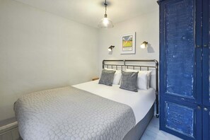 A bedroom with a bed, a blue door, and a wall-mounted light fixture.