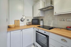 A kitchen with white cabinets, a wooden countertop, a toaster, a microwave, and an oven.