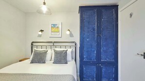 A bedroom with a bed, two wall-mounted lamps, a framed picture, and a blue door. - Host & Stay | Dodds Lane (Alnwick)