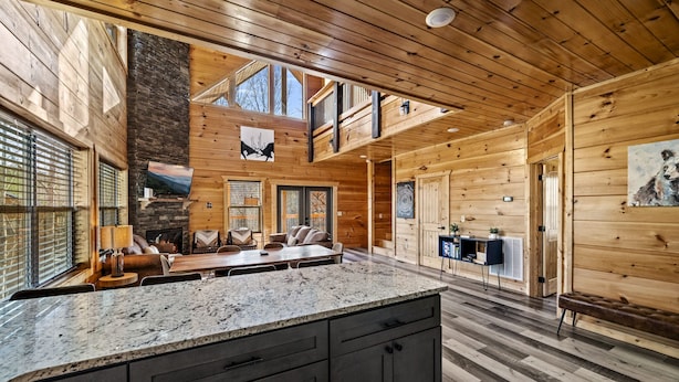 A spacious kitchen with a granite countertop, a fireplace, and a dining area with a large table and chairs. - Luxurious 3BD Lodge with POOL! Hot Tub + Games! (Sevierville)