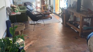 A spacious living room with a brick floor, a large window, and a wooden ceiling.