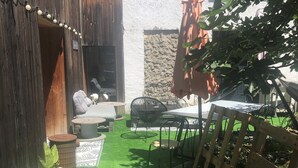 A patio area with artificial grass, outdoor furniture, and potted plants.