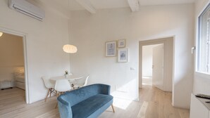 A modern living room with a blue sofa, a white dining table with chairs, and framed pictures on the wall. - Torrigiani View by Mmega (Florence)