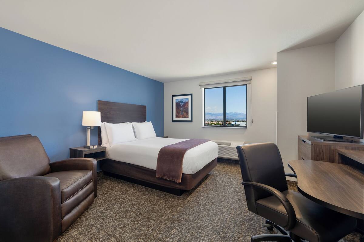 Ein Hotelzimmer mit Bett, Schreibtisch, Fernseher, Stuhl und Bergblick.