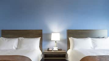 Habitación de hotel con dos camas, una mesita de noche con lámpara y un teléfono.