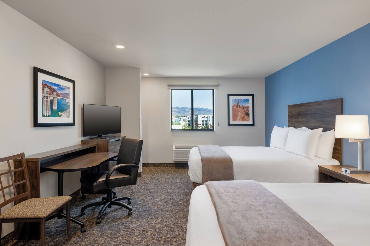 Ein Hotelzimmer mit Bett, Schreibtisch mit Stuhl, Fernseher und Fenster mit Blick auf die Stadt.