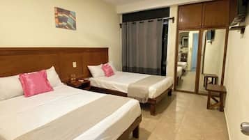 Habitación de hotel con dos camas, un ventilador de techo, un cuadro en la pared y un espejo.