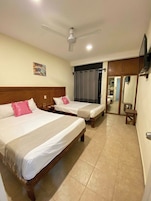 A hotel room with two beds, a ceiling fan, a painting on the wall, and a mirror.