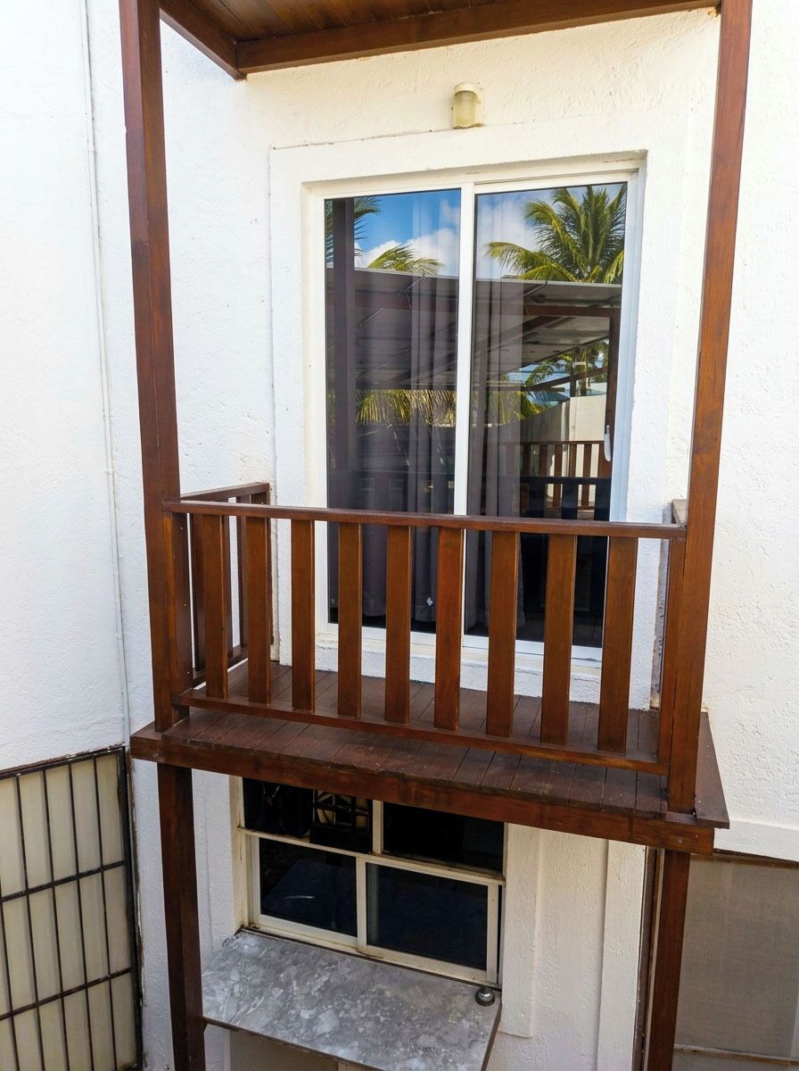 Un balcon avec une balustrade en bois, une fenêtre et une porte.