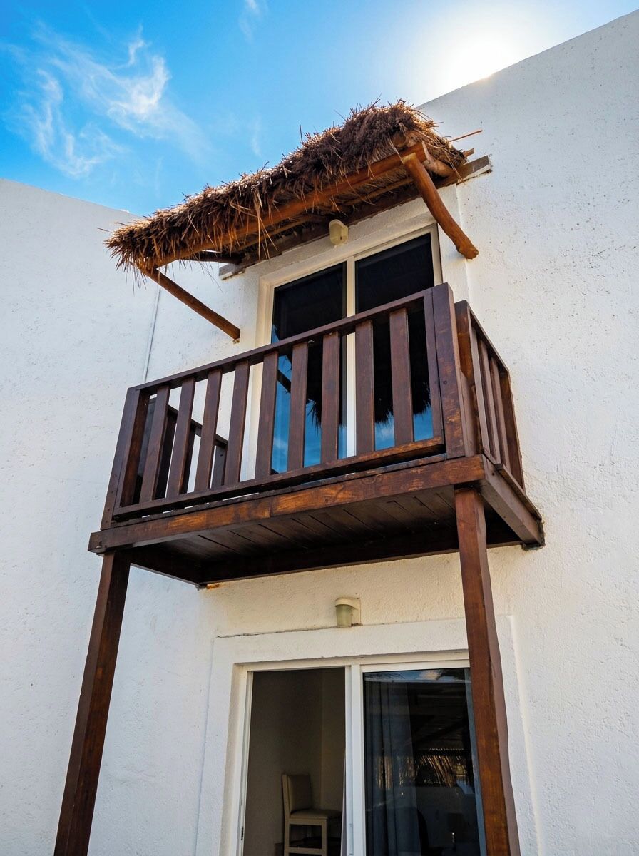 A balcony with a wooden railing and a thatched roof structure.