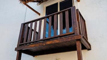 A balcony with a wooden railing and a thatched roof structure.