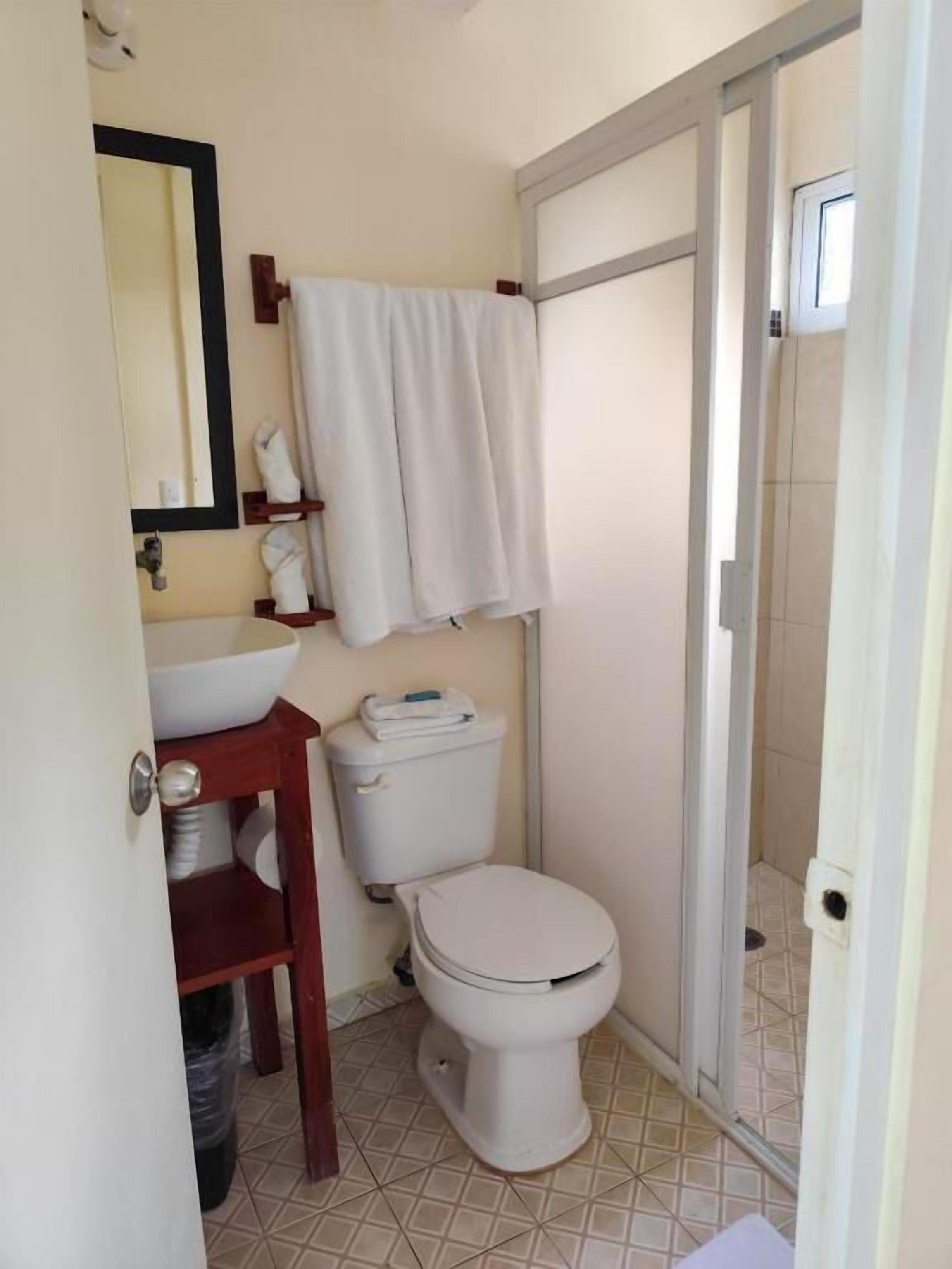 Un baño pequeño con inodoro, lavamanos y una toalla colgada en la pared.