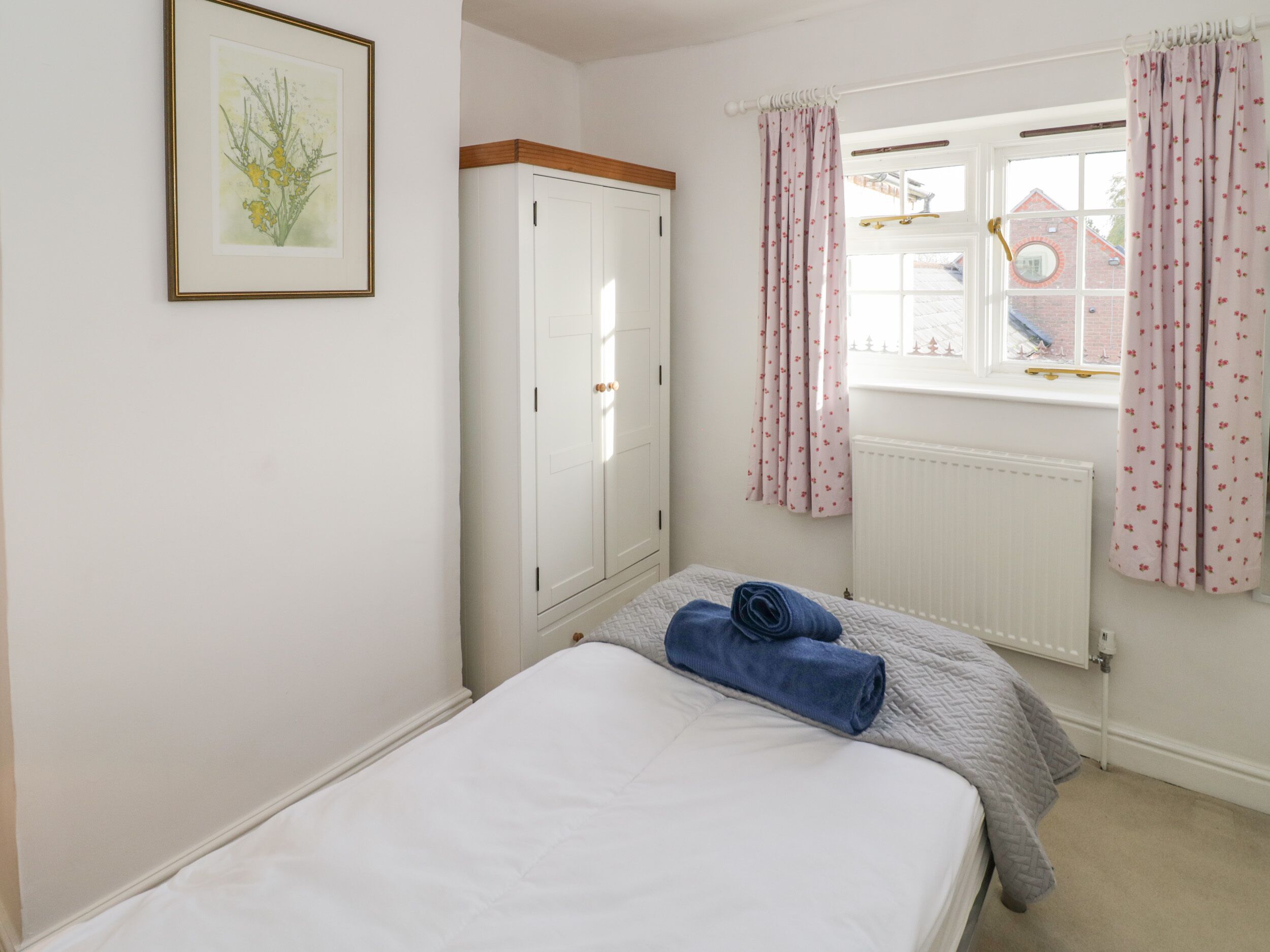 Un dormitorio con una cama, un armario y una ventana con cortinas.