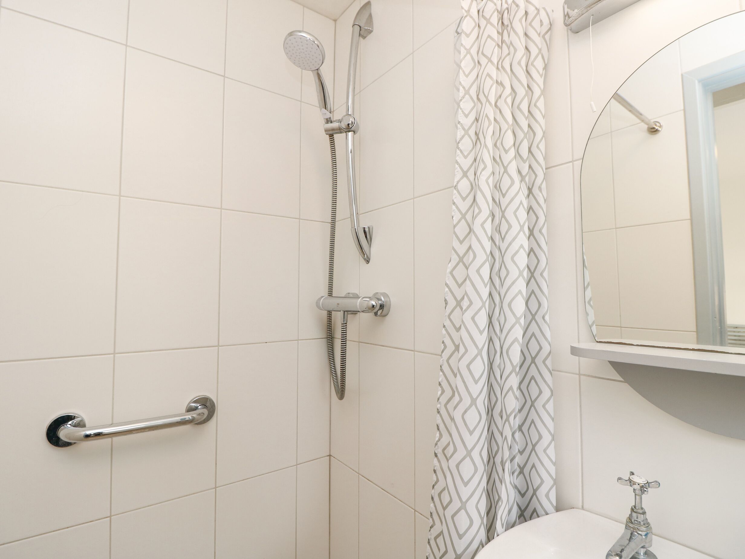Une salle de bain avec une douche, des toilettes et un miroir.