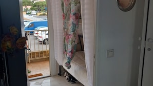 A room with a bed, a door with a mirror, and a view of parked cars outside. - Studio Trés Cocooning Pour Couple Aimant la Tranquillité, Avec Enfants (Gruissan)